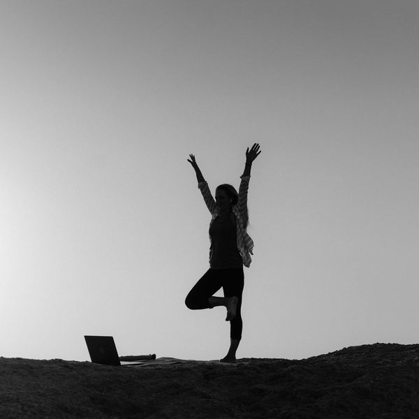 Silhouette of a person in a powerful yoga pose at sunrise.